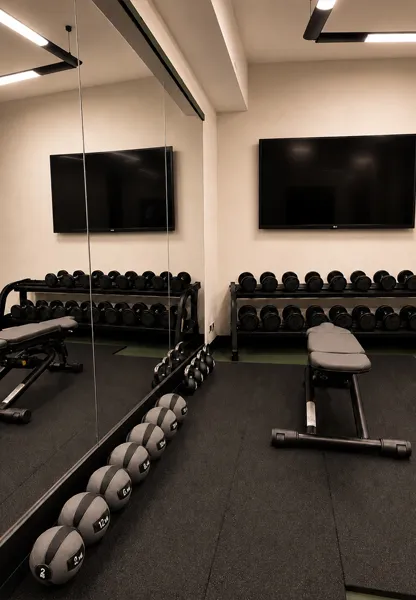 Free weights, medicine balls and workout benches in the mirrored hotel fitness room